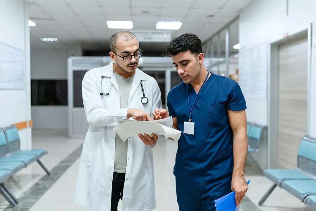 Doctors discussing medical documents in hospital corridor.
