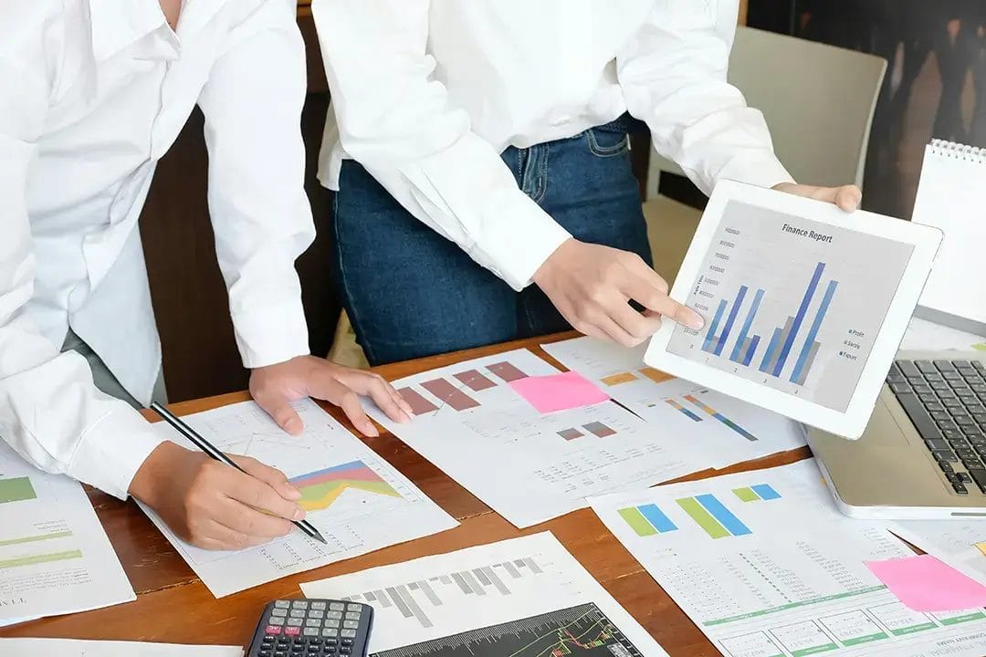 Team analysing financial charts and graphs on tablet.