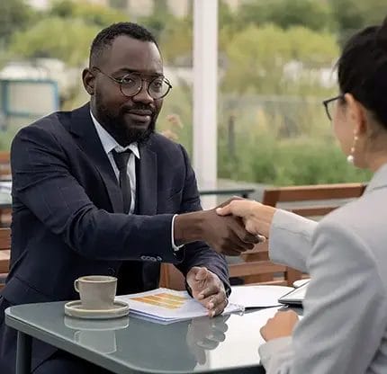 Business professionals shaking hands over coffee.