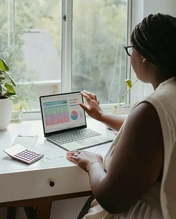 Woman analysing data on laptop near window