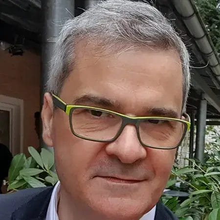 Man with grey hair and green glasses.