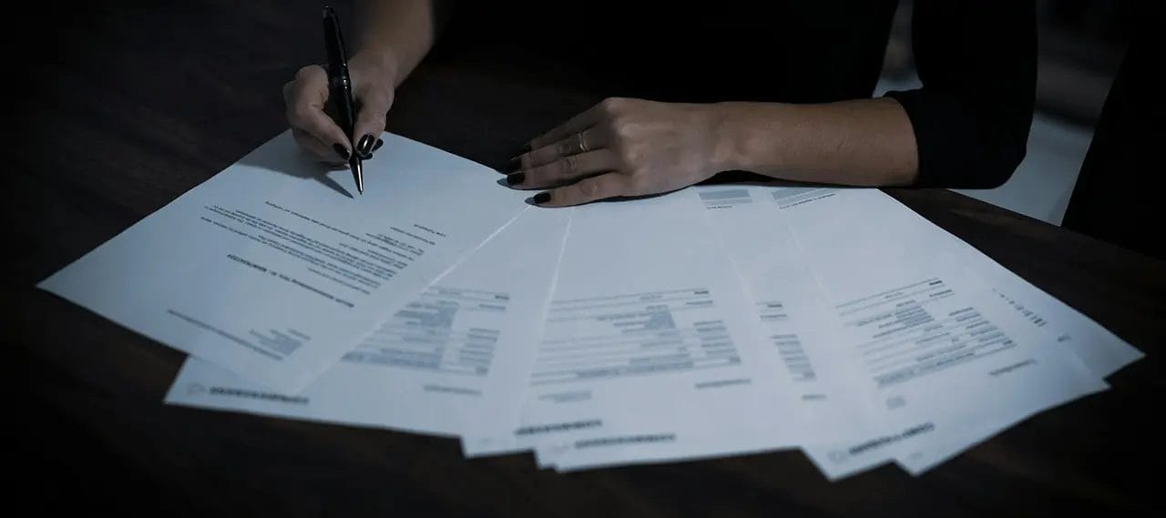 Person signing contract at desk